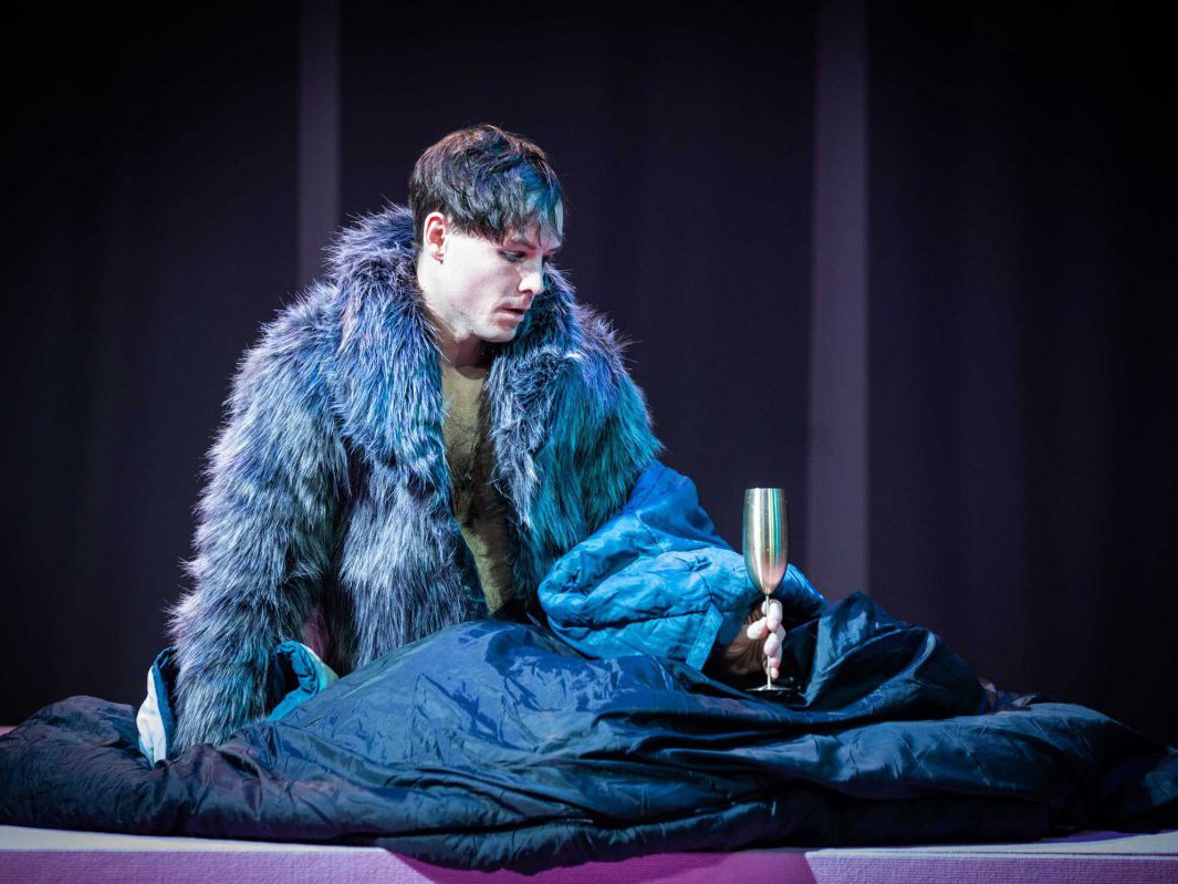 Raphael Nicholas mit Pelzmantel in Schlafsack, Reigen, TAG Theater Raphael Nicholas mit Pelzmantel in Schlafsack, Reigen, TAG Theater