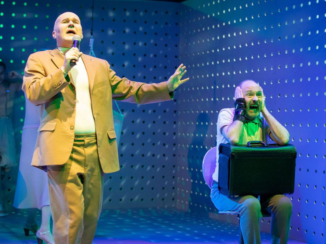 Georg Schubert singend mit Mikro und Jens Claßen mit Aktenkoffer, Die Ratten, TAG Theater Georg Schubert singend mit Mikro und Jens Claßen mit Aktenkoffer, Die Ratten, TAG Theater